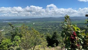 Une vue panoramique sur un paysage avec un ciel dégagé, des champs verdoyants et des montagnes lointaines.