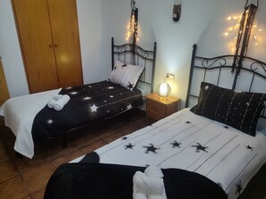 Un dormitorio con dos camas, una mesita de noche con lámpara y ropa de cama con estampado de estrellas.