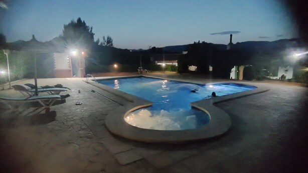 An outdoor swimming pool with a hot tub, surrounded by a paved area with lounge chairs and a small deck. - Country House 'El Serrano' with Mountain View, Wi-Fi and Air Conditioning (Murcia)