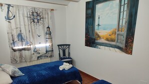 A room with two beds, a chair, a table, and a wall with nautical-themed artwork. - Country House 'El Serrano' with Mountain View, Wi-Fi and Air Conditioning (Murcia)