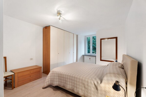 A bedroom with a bed, a dresser, a mirror, and a window.