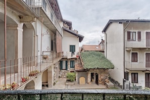 Una calle estrecha con edificios que tienen balcones, una tienda pequeña y un toldo verde.