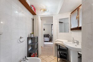 A bathroom with a white sink, a mirror, and a shower area.