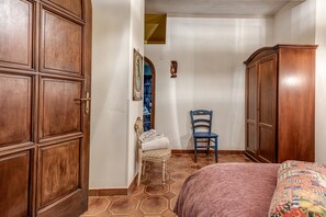 Un dormitorio con una cama, un armario de madera, una silla y una mesita.