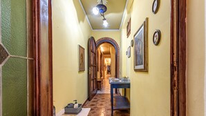 A hallway with a tiled floor, wooden doors, and framed pictures on the walls. - Room 'Matroniale 3' with Wi-Fi and Air Conditioning (Firenze)