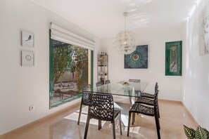 Ein Essbereich mit einem Glastisch, Stühlen, einer Chandelierleuchtre und Kunstwerken an den Wänden.