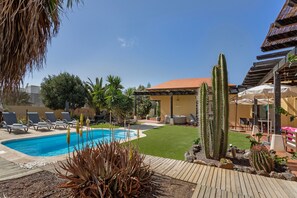Ein Poolbereich mit Liegestühlen, einem Kakteengarten und einem Gebäude mit rotem Dach.