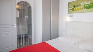Een slaapkamer met een bed, een deur met spiegel en een muur met een schilderij.