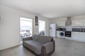 Un apartamento moderno con sofá, cocina y vistas a través de la puerta.