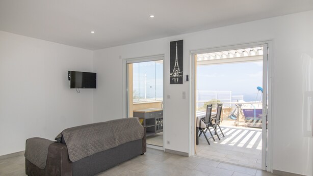 Een moderne woonkamer met een bank, een flatscreen televisie en een balkon met uitzicht.