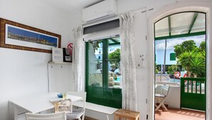 Una habitación con una mesa de comedor, sillas, un taburete de madera pequeño y vistas al exterior.