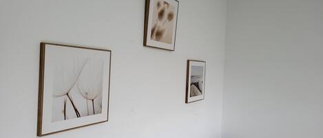 Una habitación con una pared blanca, un sofá marrón y tres cuadros enmarcados.