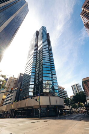 A tall, modern building with a glass facade, surrounded by other high-rise structures.
