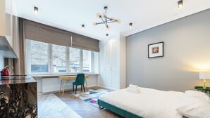 Moderni makuuhuone, jossa on suuri sänky, työpöytä ja tuoli.