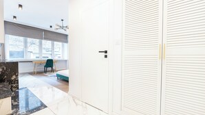 Moderni huone, jossa on marmorilattia, puinen työpöytä, turkoosinsininen tuoli ja valkoinen liukuovellinen vaatekaappi.