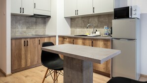Cocina moderna con armarios de madera, microondas integrado, refrigerador y un taburete de bar.