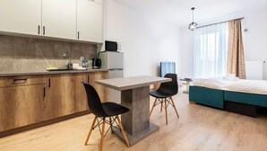 Cocina moderna con comedor, cama y ventana con cortinas.