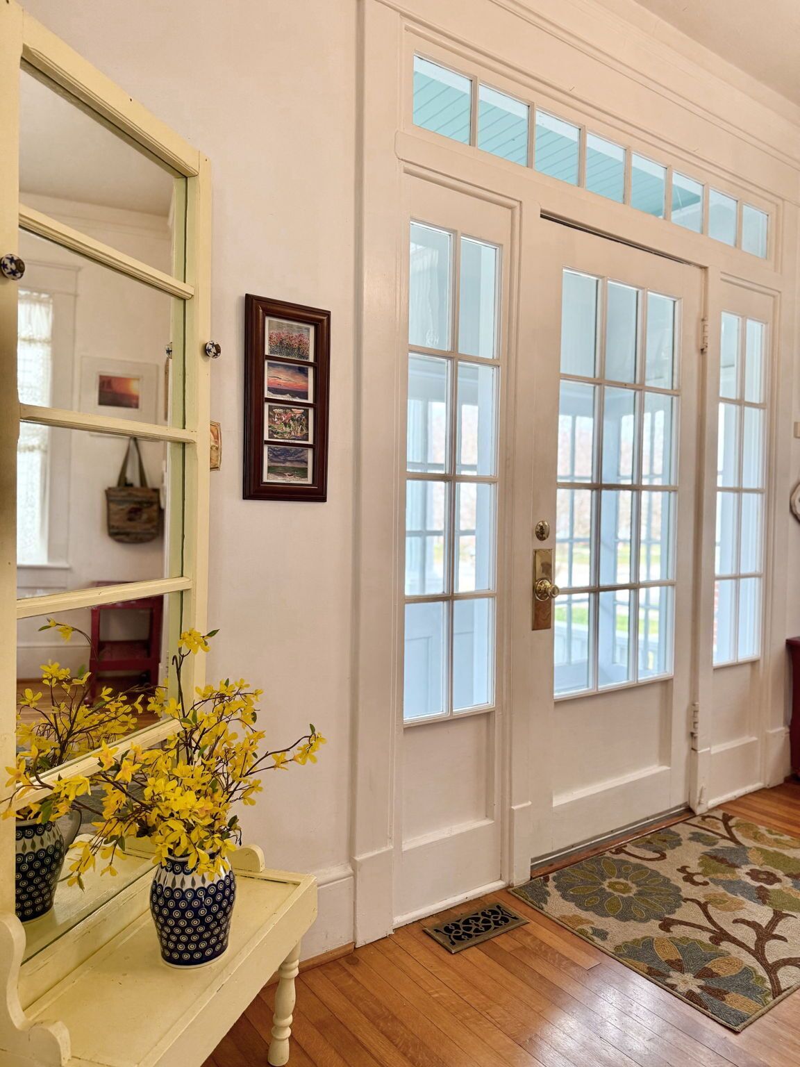 A hallway with a wooden bench, a mirror, and a door with glass panels.