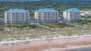 A beachfront hotel with multiple buildings, a swimming pool, and a boardwalk.