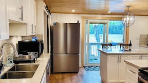 Una cucina moderna con soffitto in legno, elettrodomestici in acciaio inossidabile e vista sull'esterno.