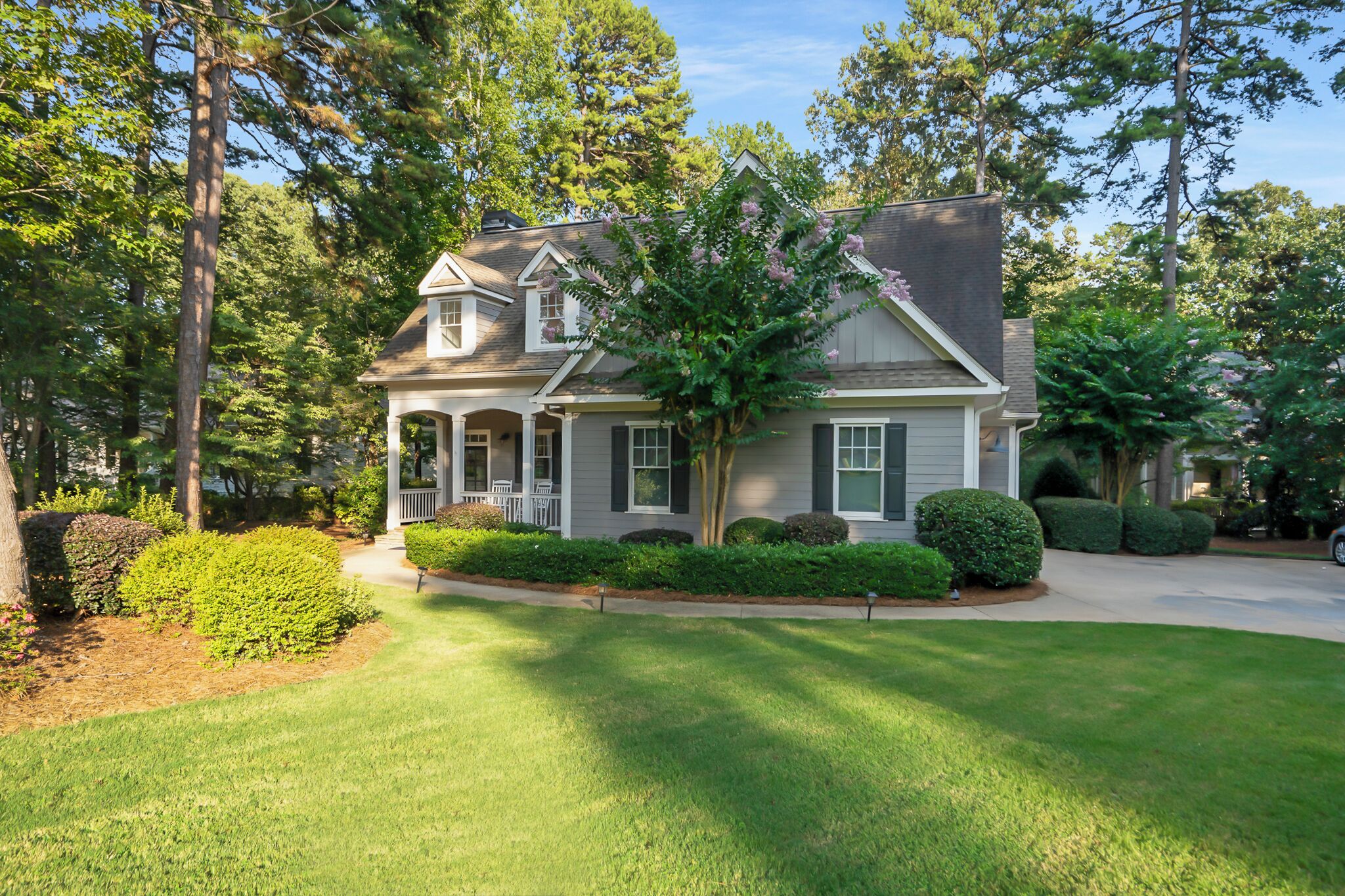 A two-story house with a front porch, surrounded by well-maintained lawns and trees.