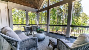 A covered outdoor area with wicker furniture, a round table, and a potted plant. - Private Pool+Game Room+Private Dock on Lake Oconee (Eatonton)
