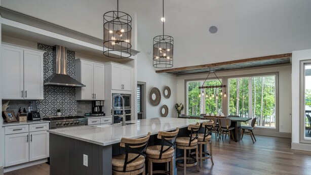 A spacious kitchen with a large island, white cabinetry, and modern appliances. There are hanging lights above the island and a large window providing natural light. - Private Pool+Game Room+Private Dock on Lake Oconee (Eatonton)