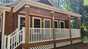 Een houten chalet met een overdekte veranda en een witte hekwerk.