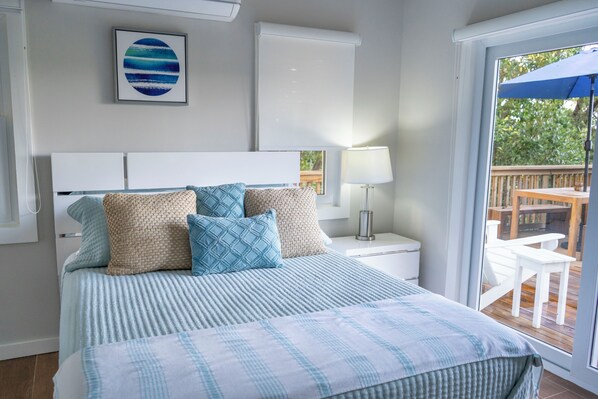 Un dormitorio con cama, mesita de noche, lámpara y vistas a una terraza.