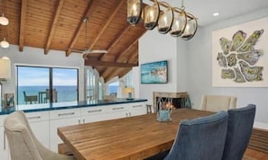 A wooden dining table with chairs, a ceiling fan, and artwork on the walls.