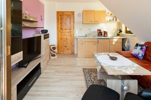 A modern kitchen with wooden cabinets, a dining area with a table, and a living space with a sofa.