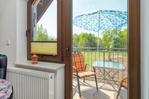 A room with a window, a radiator, a table with chairs, and an umbrella outside.
