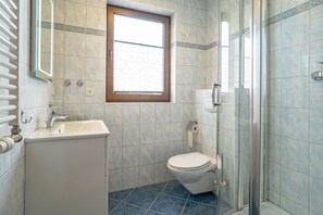 Un baño con lavamanos, inodoro y cabina de ducha de vidrio.