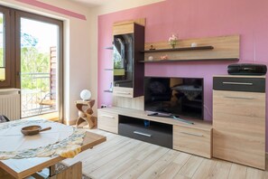 Una cocina moderna con una tele grande, armarios de madera y una zona de comedor con una mesa para dos.
