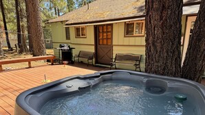 A hot tub on a wooden deck with a house in the background.