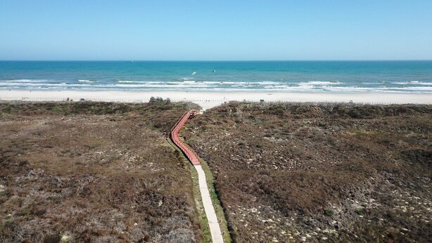 A coastal path leading to a beach with a clear view of the ocean.