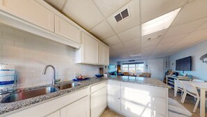 A modern kitchen with white cabinets, granite countertops, and a large island.