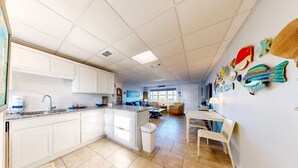 A spacious kitchen with white cabinets, a granite countertop, and a tiled floor.