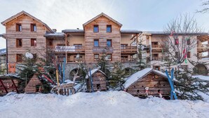 A wooden building with multiple balconies and a sign that reads "LES BALCONS DE L'ISO". - Escapade alpine | Piscine, sauna & vue montagne (Abriès)