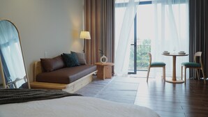 Ett hotellrum med en säng, en soffa, ett litet bord med stolar och utsikt över omgivningarna.