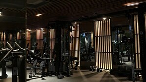 Ett gym med träningsutrustning, träribbor i taket och en spegel.