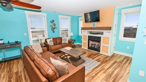 A living room with a brown leather sofa, a wooden coffee table, and a fireplace. - Oceanside, Wild Horses, Private Pool, Hot Tub -4x1941, A Sense of Porpoise (Carova Beach)