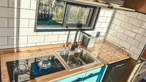 A modern kitchen with a gas stove, stainless steel sink, and wooden countertop. - Cozy cabin with the best sunset! (Morungaba)