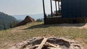 A fire pit in a grassy area with a covered seating area and a building in the background. - Cozy cabin with the best sunset! (Morungaba)