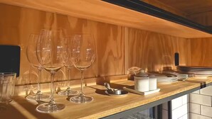 A wooden interior with a long counter displaying wine glasses and dining ware. - Cozy cabin with the best sunset! (Morungaba)