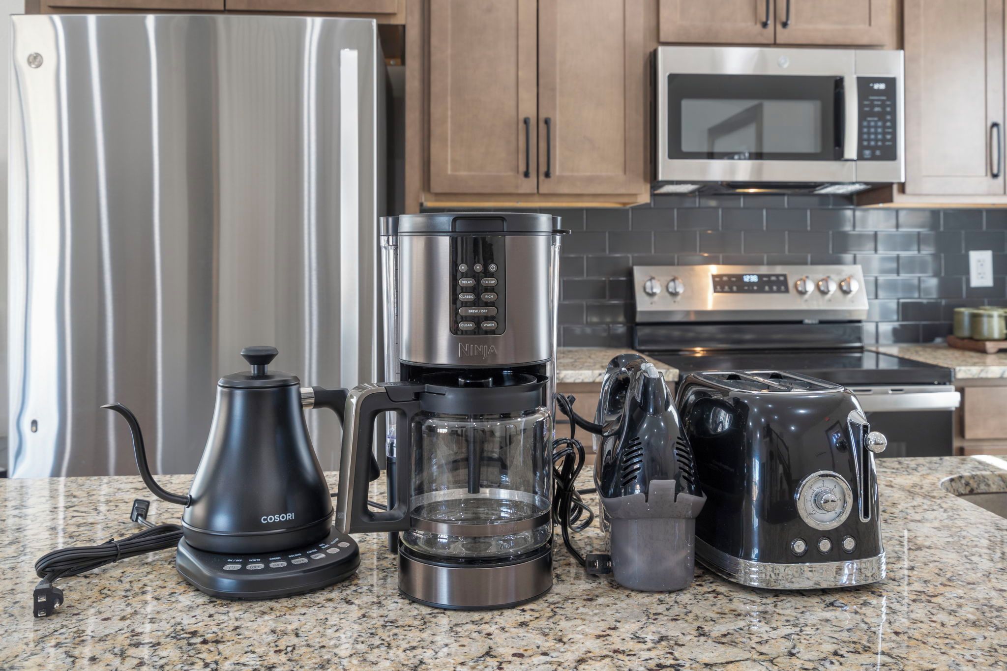 A kitchen with a stainless steel refrigerator, a coffee maker, a toaster, and a microwave.