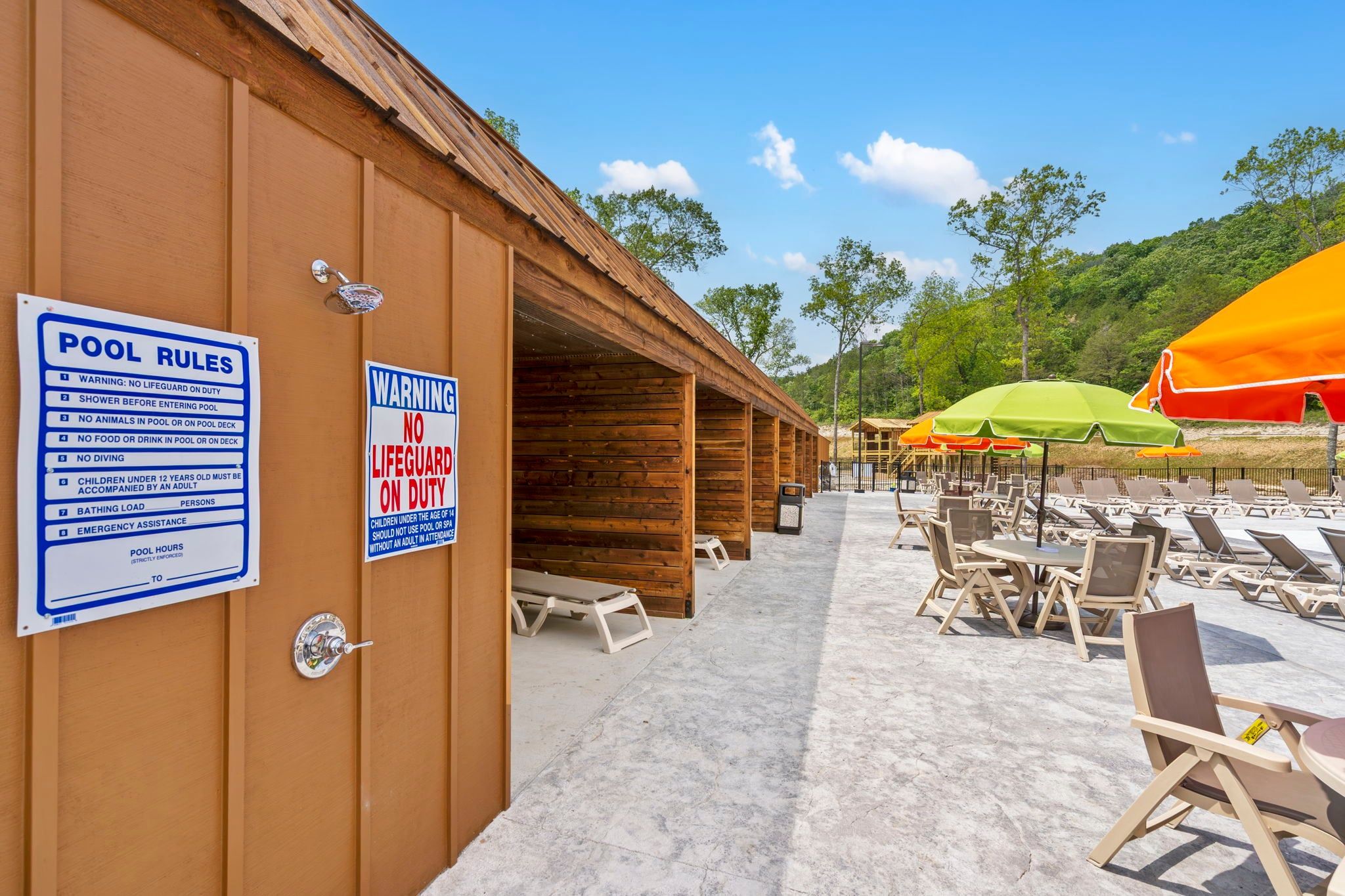 A pool area with wooden cabins, lounge chairs, and umbrellas.