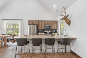 Una cocina moderna con una isla grande, taburetes de bar y una cabeza de ciervo montada.