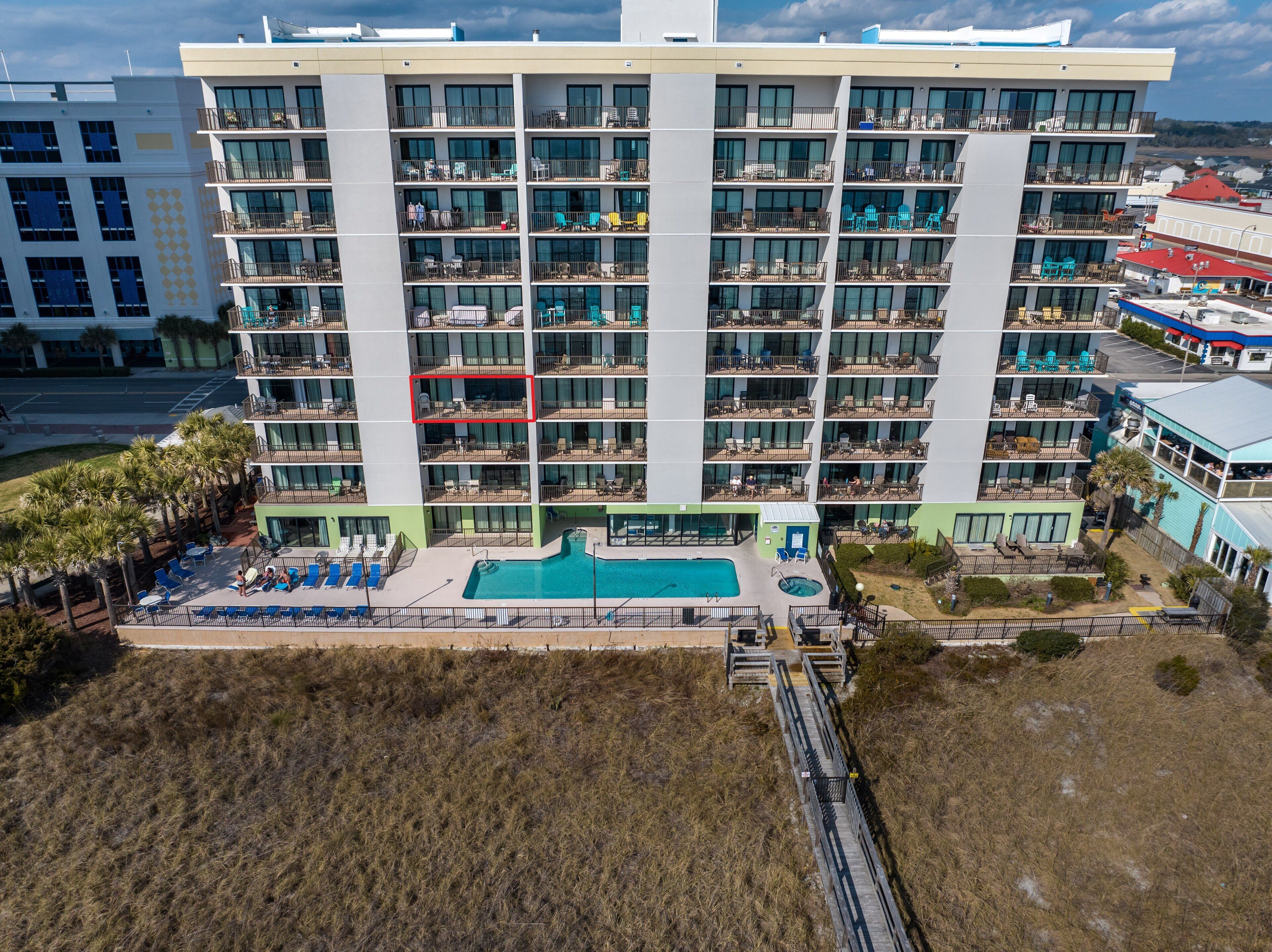 Un hotel de varios pisos con balcones, piscina y zona de playa.