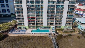 Un hotel de varios pisos con balcones, piscina y zona de playa.